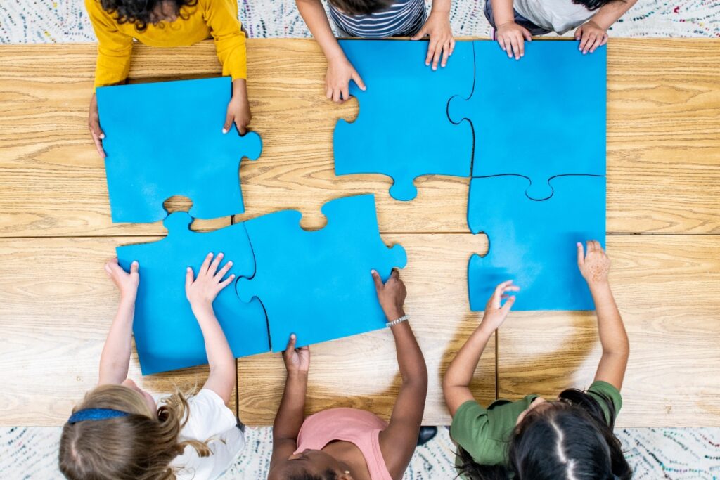 Enfants assemblant un puzzle géant bleu, symbole d’inclusion TSA