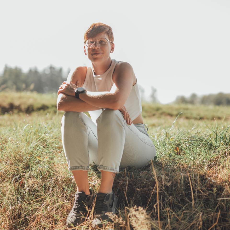 Portrait de la fondatrice de Parlons TSA, assise dans un champ, souriante – accompagnement autisme humain et bienveillant