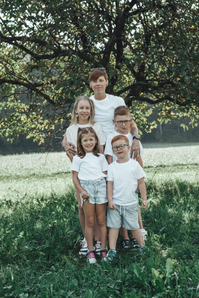 Photo de famille avec Virginie Müller et ses quatre enfants, tous souriants sous un arbre – lien familial au cœur du projet Parlons TSA